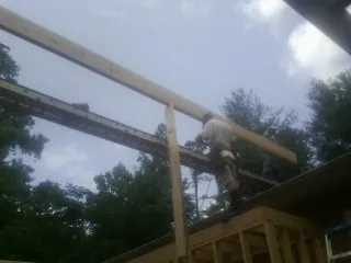 Carpenter setting a ridge beam over a new addition frame — Ice Dam Removal by Roofing Brothers in Waddell