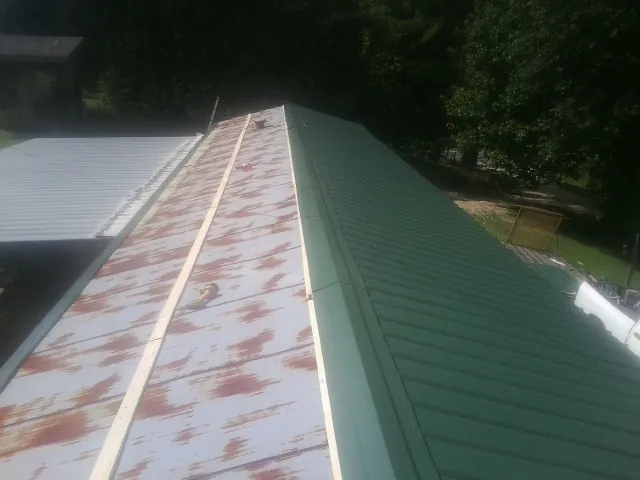 Old rusted panels beside newly installed green metal roofing — Wind Damage Roof Repair by Roofing Brothers in Waddell