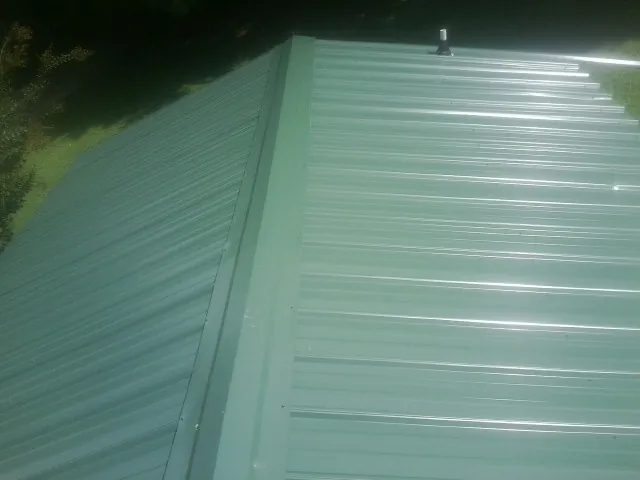 New green metal panels meeting at the ridge of a roof — Flat Roof Repair work by our crew in Waddell