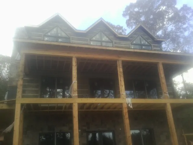 Dormers and porch framing on a large log home under construction — Roof Coating work by our crew in Waddell