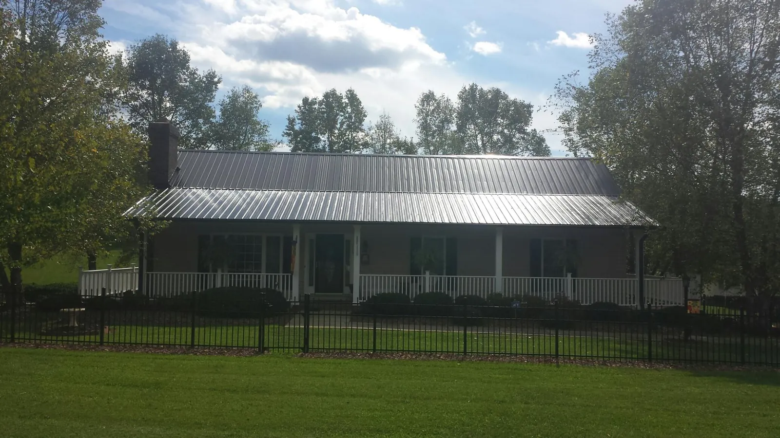Gray metal roof on a brick ranch with a full width front porch — Gutter Guard Installation work by our crew in Waddell