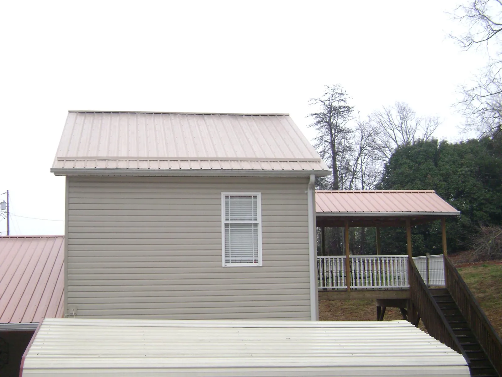 Tan metal roofs on a two story addition and attached porch, from a Roof Replacement job in Waddell