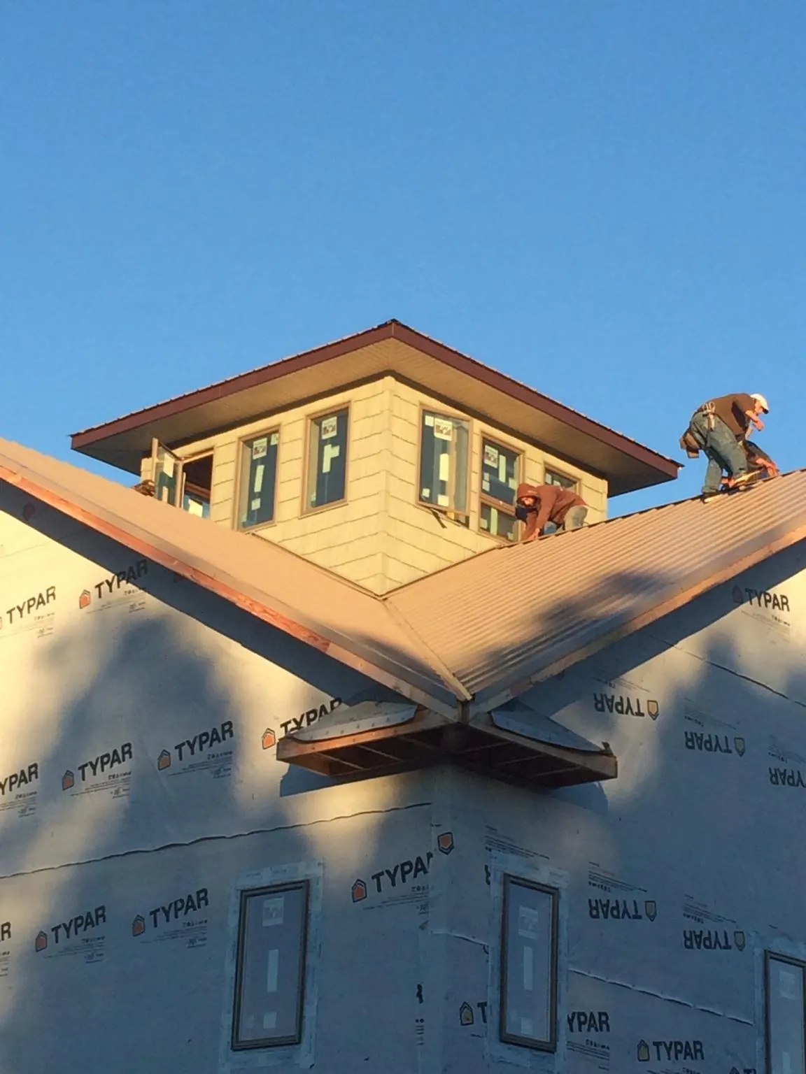 Roofers working around a rooftop cupola on a new metal roof at sunset — Roof Waterproofing in Waddell by Roofing Brothers